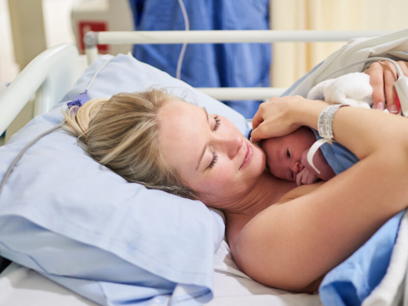Mother with newly born child in hospital maternity ward bed