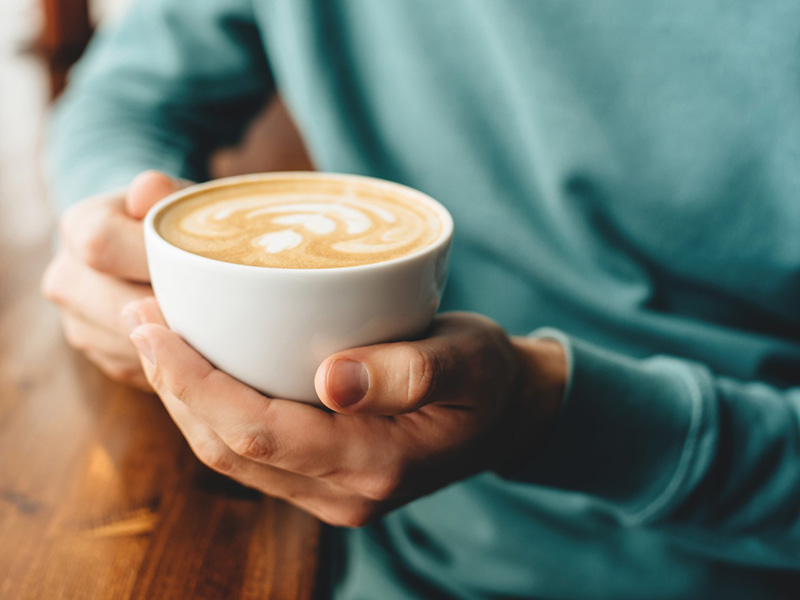 Person holding a cup of coffee Person holding a cup of coffee