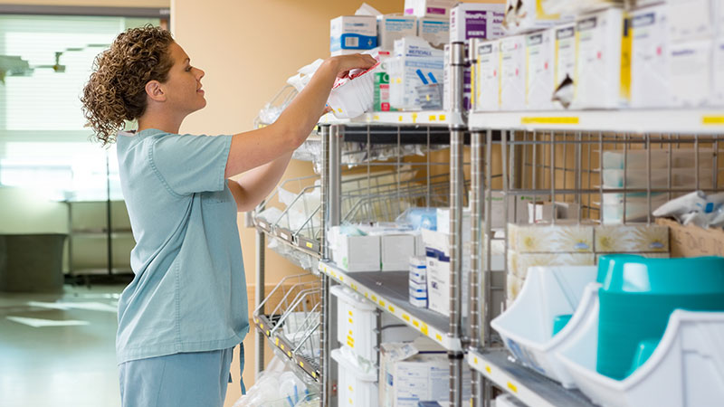 Image of female clinician reaching for a product in a store room