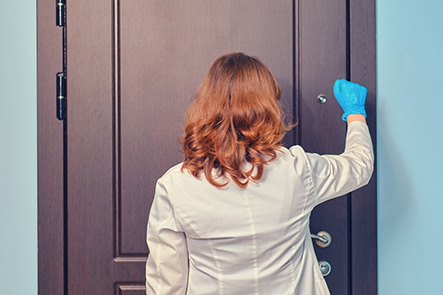 Woman doctor knocks on door of apartment.