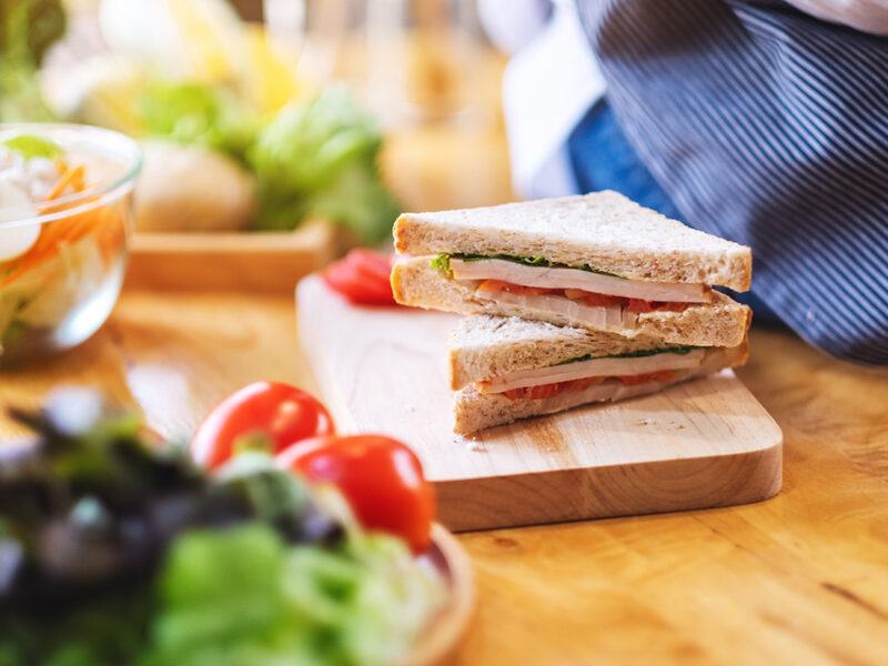 Sandwich on a chopping board, with salad nearby