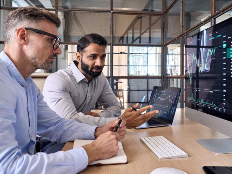 Graphical data on screen with two office workers Graphical data on screen with two office workers