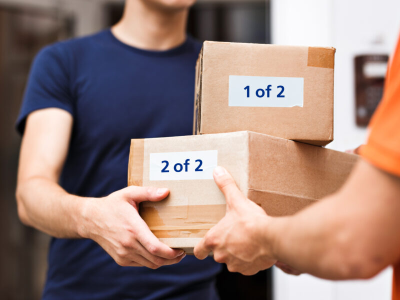 Man handing over two parcels to another man