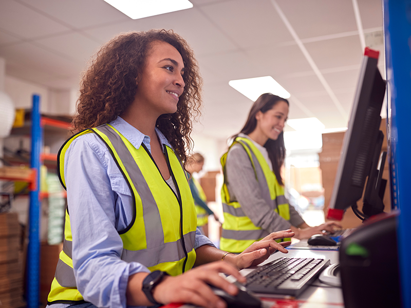 Female staff on computers in a warehouse Female staff on computers in a warehouse