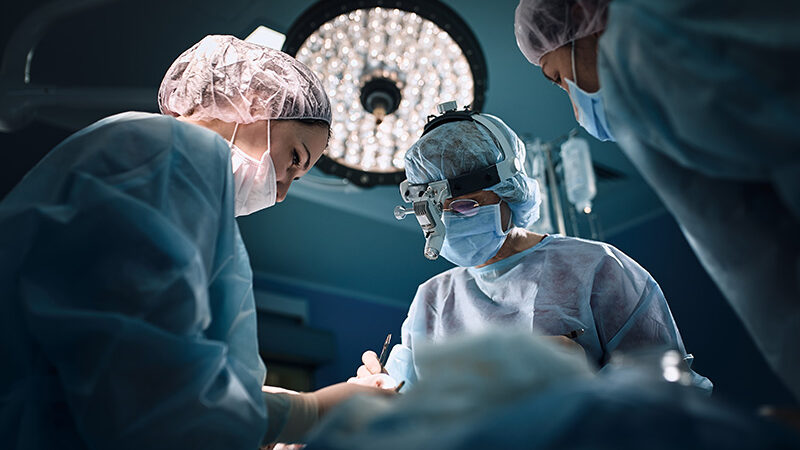 Inside an operating theatre with three medical staff.
