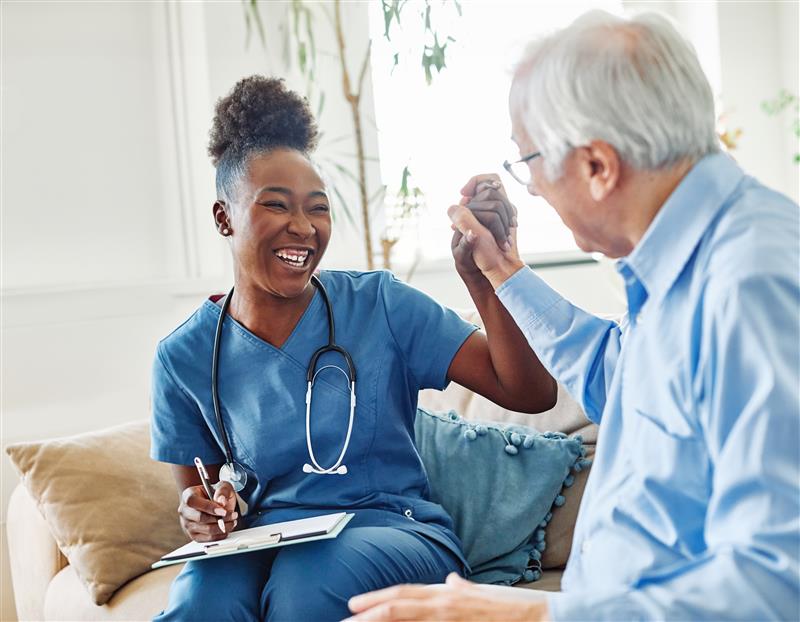 Smiling Caregiver high-fiving with older patient Smiling Caregiver high-fiving with older patient